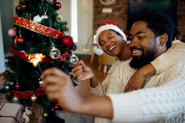 うれしそうなアフリカ系アメリカ人の女性と彼女の夫は家でクリスマスの日に楽しんでいます