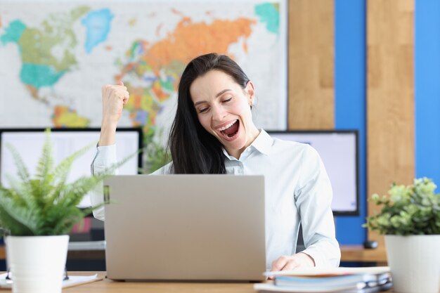 Joyful amazed woman looks into laptop at workplace