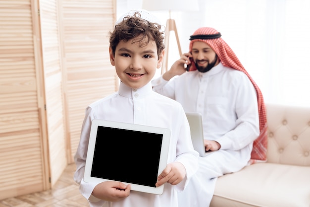 Photo joyful arab boy presents a new black tablet