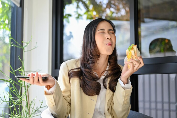 Photo 카페에서 샌드위치를 먹는 그녀의 건강한 아침 식사를 즐기는 즐거운 아시아 사업가