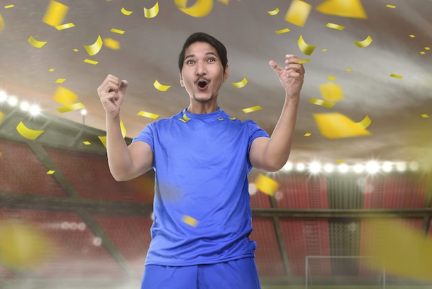 Joyful asian football player man with excited expression