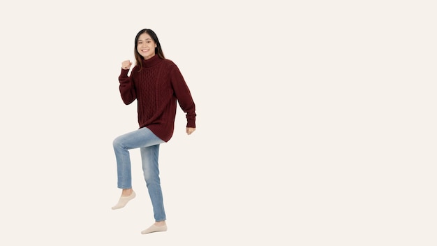 A joyful Asian woman stands against an isolated white background in a cute fullbody pose