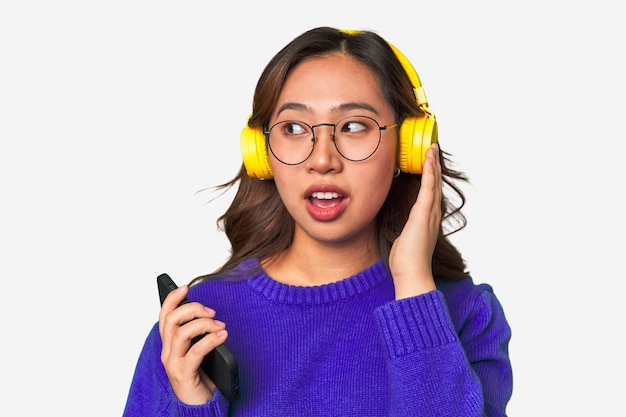 Joyful Asian woman wearing headphones enjoying music and having fun