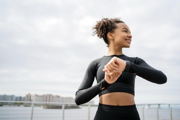 Joyful athlete stretching before a run smartwatch on wrist with a city waterfront backdrop