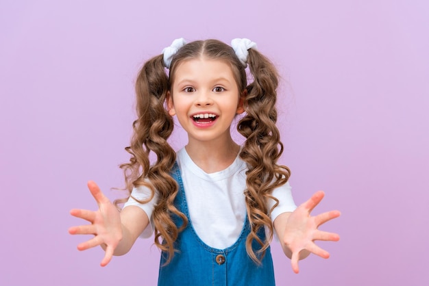 The joyful baby stretched out her hands and asked for something Please give me a thing A child with long curly hair on an isolated background