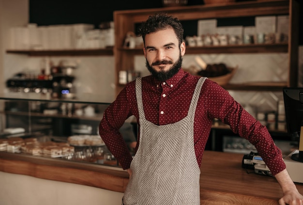 Joyful barista looking at camera in cafe