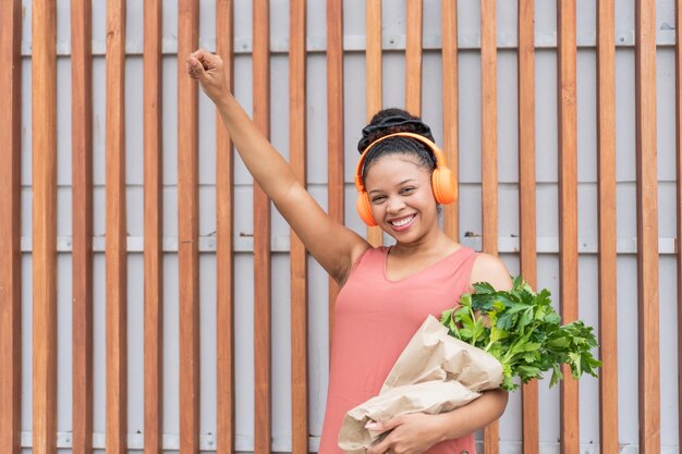Photo joyful beat victorious woman with music and greens
