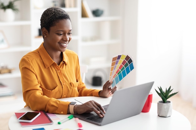 Joyful black lady working as web designer office interior