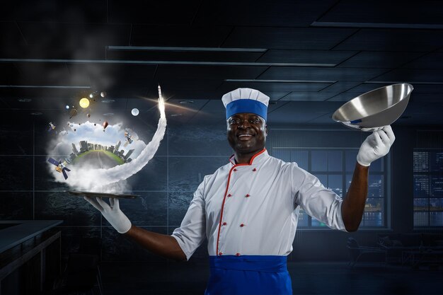 Photo joyful black man wearing an apron and cooking in action. mixed media