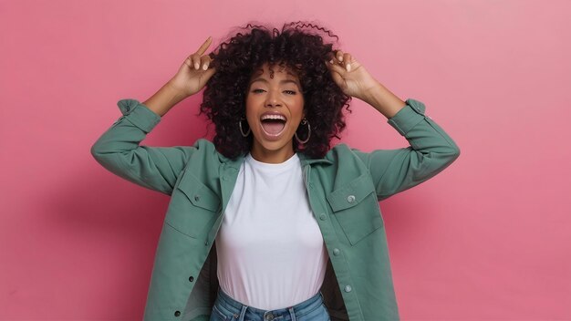 Joyful black woman having fun in studio over pink background white tshirt green jacket