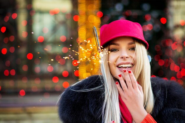 Joyful blonde girl celebrating Christmas with sparklers