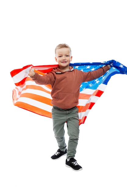 Радостный мальчик держит в руках развевающийся американский флаг. День Независимости и патриотизм. Изолированные на белом фоне. Вертикальный.