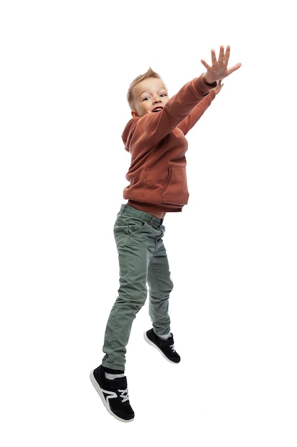 Веселый мальчик прыгает. Парень в джинсах и коричневом свитере. Активность и движение. Изолированные на белом фоне. Вертикальный.
