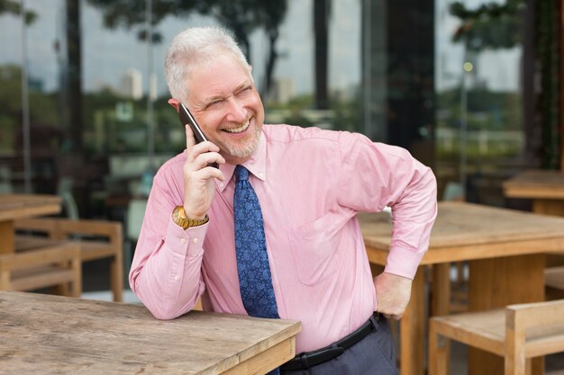 Joyful Business Man Talking on Phone in Cafe