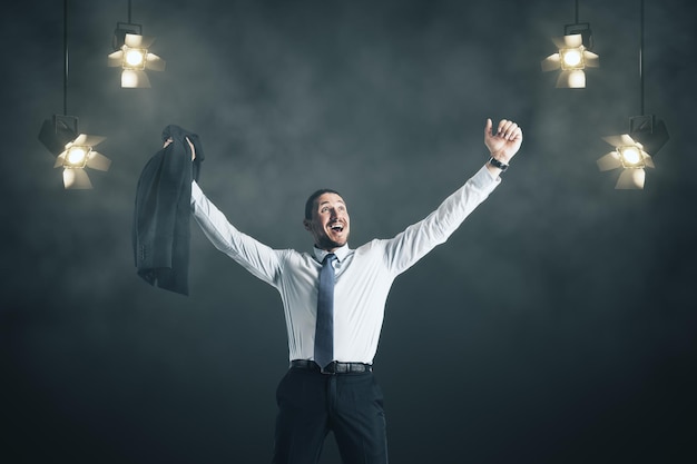 Joyful businessman performance on smoky background with spotlights