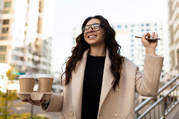 Joyful businesswoman at the beginning of the working day with cups of coffee and a smile on her face