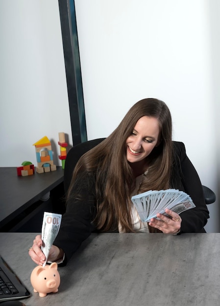 Photo joyful caucasian businesswoman putting the paper money into piggy bank and smile with happiness for money saving to wealthness in the future of education concept woman puts in the moneybox cash