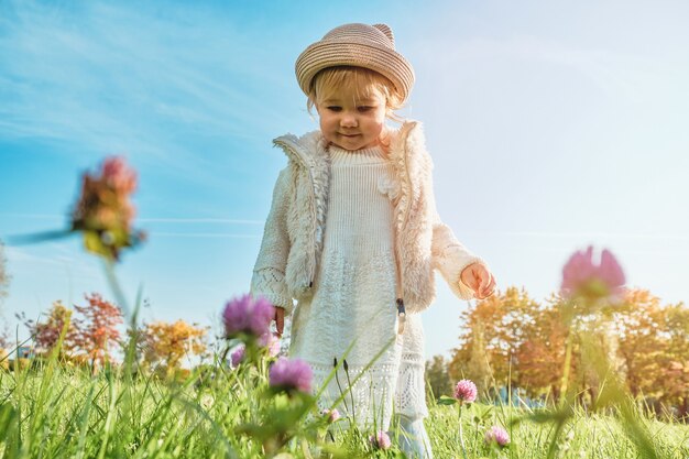 A joyful caucasian child girl stands in a field of clovers flowers