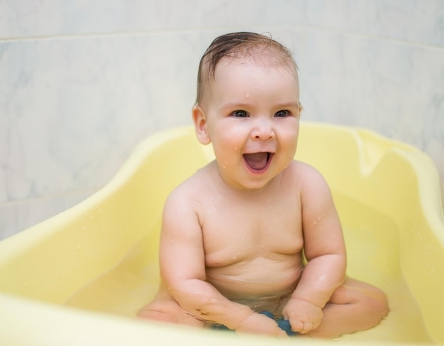 A joyful child is sitting in the bathtub Baby with a charming smile bathes