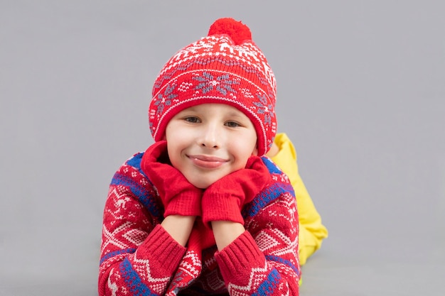 Joyful child in winter clothes on a gray background