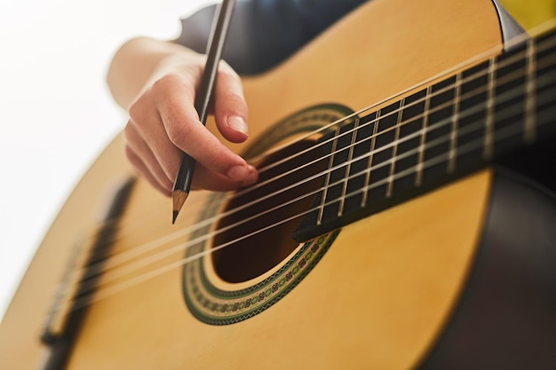 Joyful child with acoustic guitar raising arms after successful performance