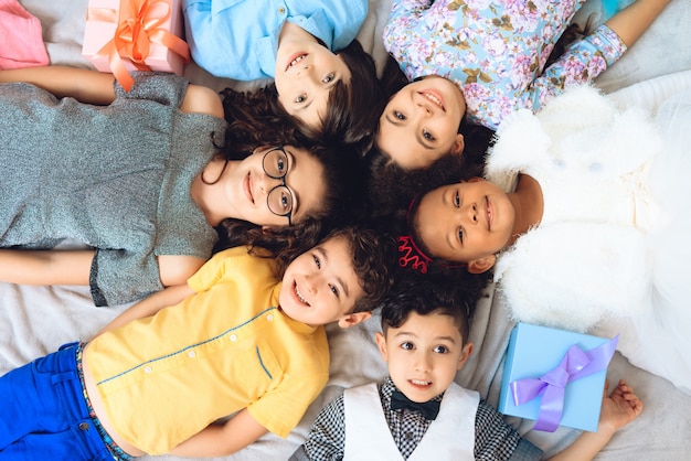 Joyful children who lie on floor in shape of circle.