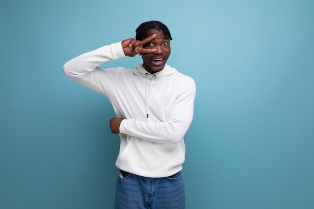 Joyful coquettish darkskinned european young brunette man in a white hoodie