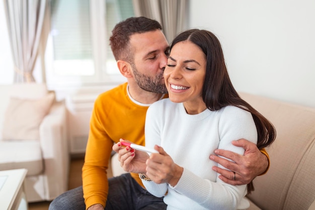 妊娠検査の結果を自宅で知った幸せなカップル 妊娠テストを見ている幸せな夫婦 女性が妊娠テストの結果が陽性で夫を驚かせている 夫はかなり満足しているようだ