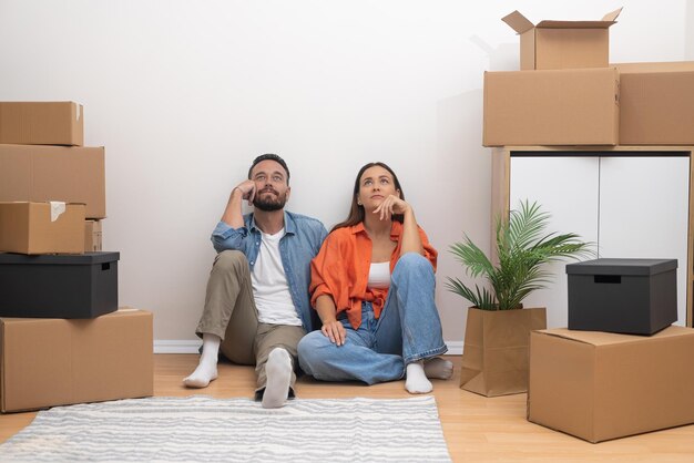 Joyful couple in new home brainstorming decor ideas unpacked boxes relocation concept