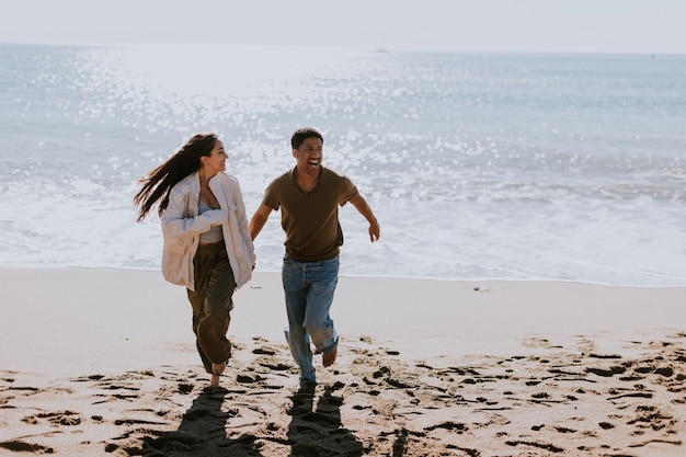 Joyful couple running hand in hand along a sunlit beach at sunset