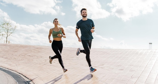 Joyful couple running on a rooftop clear blue sky above and city horizon in view