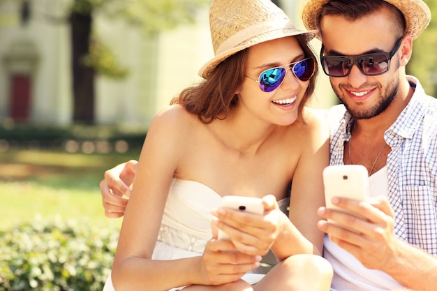 a joyful couple using smartphones in the park