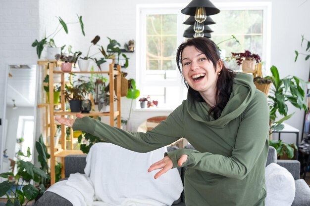 Joyful emotions of a woman in her home in a bright modern interior with home plants Ecofriendly portrait with real joy