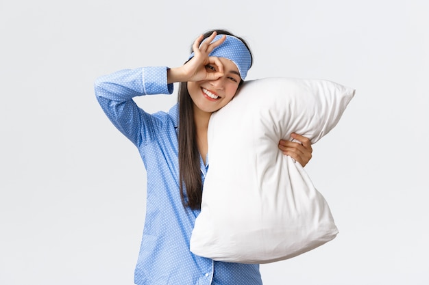 Joyful enthusiastic beautiful asian girl in blue pyjama and sleeping mask