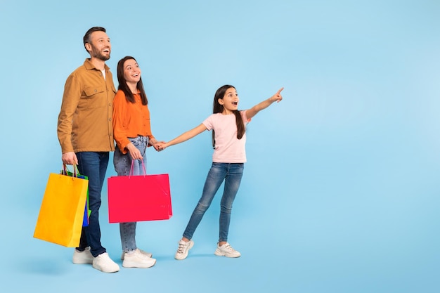 Foto famiglia gioiosa dopo la spesa che indica con il dito lo studio dello spazio vuoto