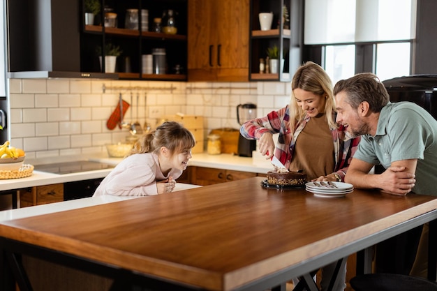 Photo joyful family enjoying homemade chocolate cake in cozy kitchen