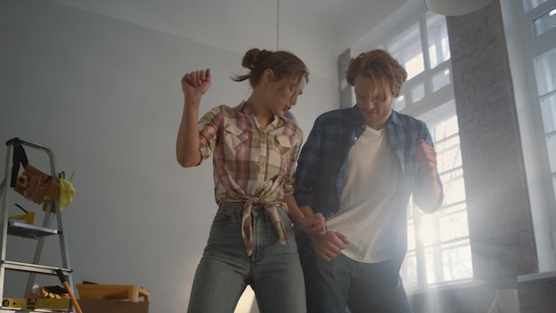 Joyful family enjoying improvement of apartment Happy couple dancing indoors