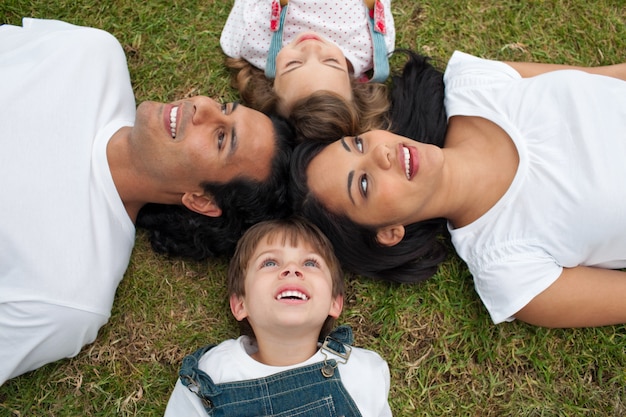 Joyful family lying in a circle on the grass 