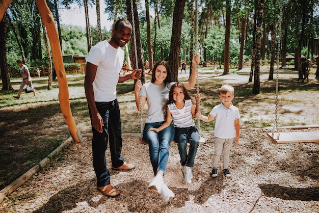 Joyful family on playground la gente oscilla nel parco