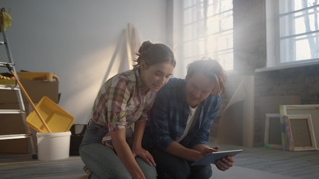 Joyful family sitting in new house Couple searching home design on tablet