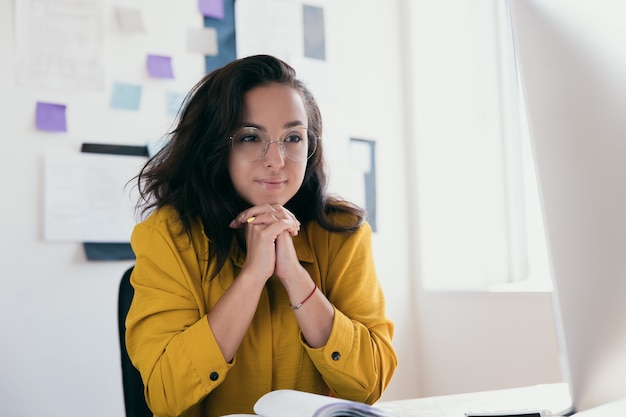 Joyful female freelance worker wear yellow blouse and round glasses