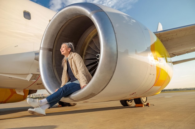 飛行前に飛行機のタービンエンジンで休んでいる間、目をそらして笑っているうれしそうな女性旅行者