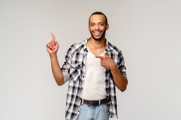 Joyful friendly african-american young man iwearing casual shirt pointing by finger