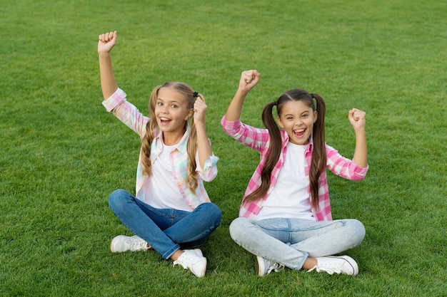 Joyful friends Sisterhood and friendship Cheerful schoolgirls on sunny day Girl ponytails hairstyle enjoy summer vacation Happy life Happy smiling friends Have fun Happy kids relaxing outdoors