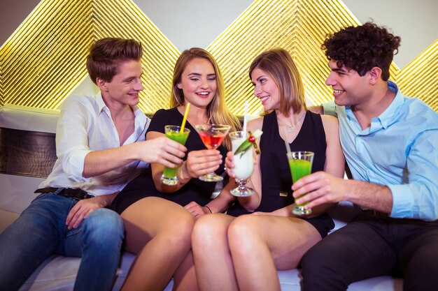 Joyful friends toasting cocktail glasses