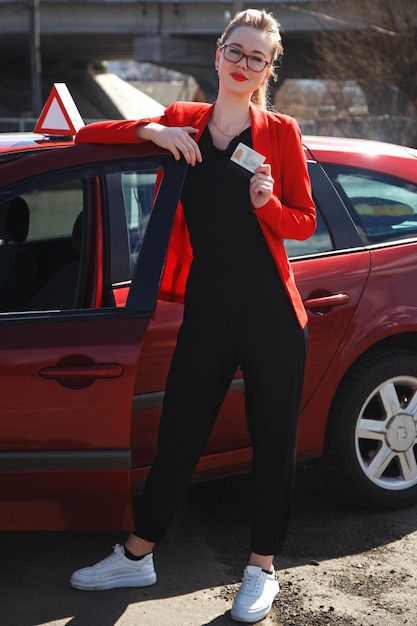 Joyful girl driving a training car with a drivers license card in her hands.