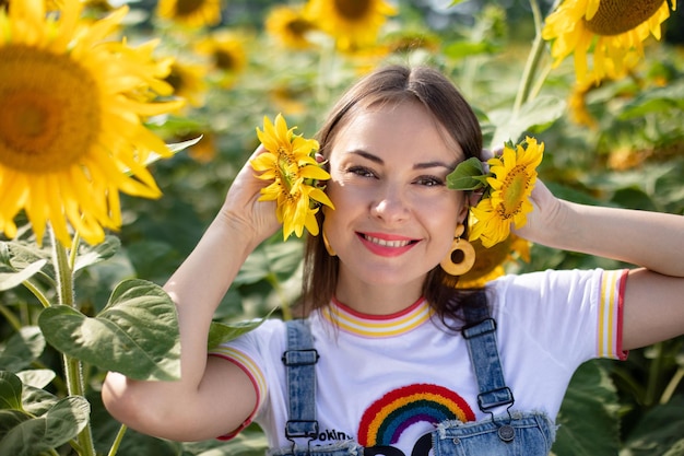 Ragazza gioiosa che scherza con i girasoli nel campo