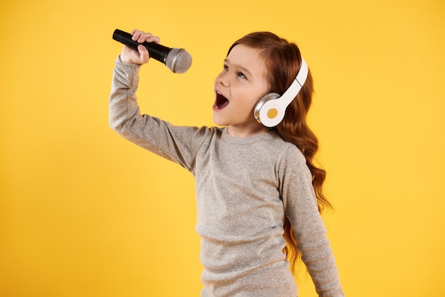 Joyful girl in headphones is singing karaoke.