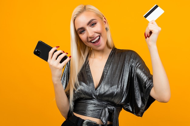 Joyful girl makes purchases through the application on the phone holding a credit card