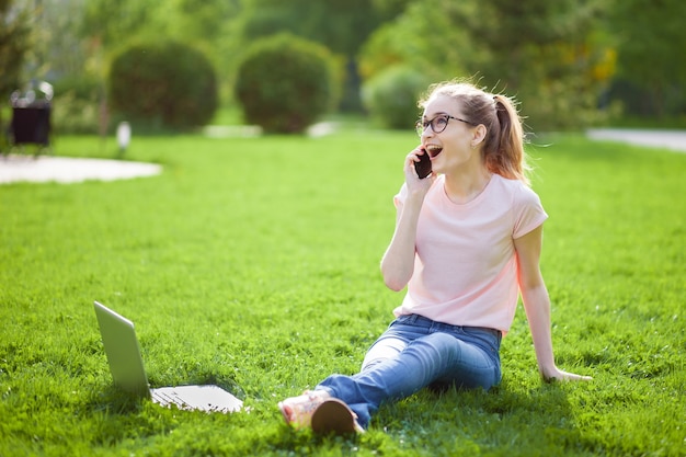 Ragazza allegra con gli occhiali, parlando al telefono nel parco